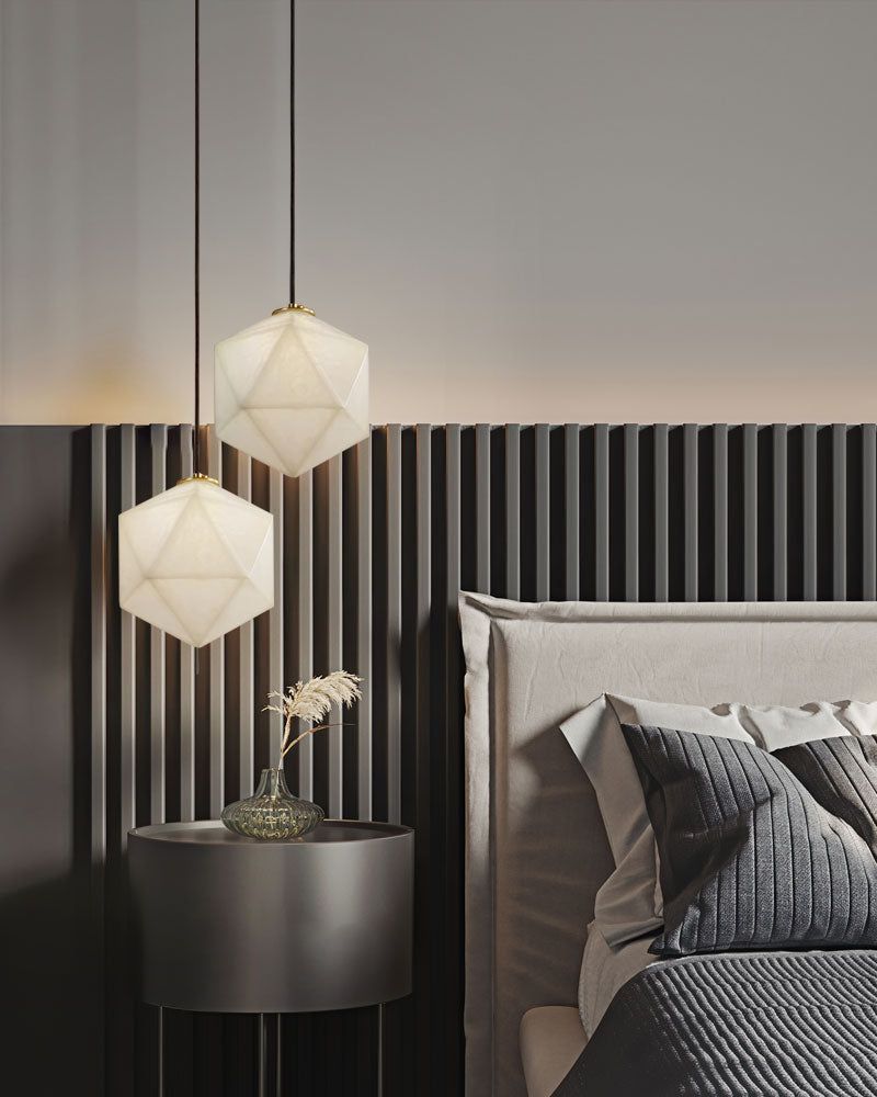 Hexagonal alabaster pendant lamps above modern grey bed with black nightstand and vase.