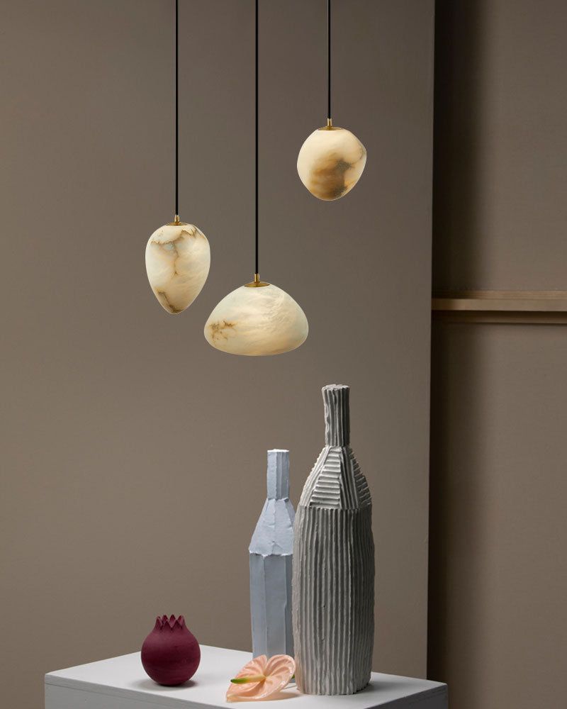 Three G9 Nature Alabaster Pebble pendant lights above decorative vases on a pedestal.