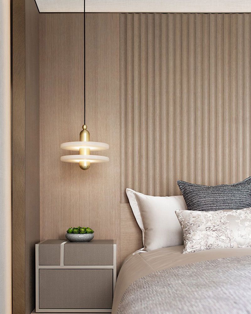 Two-tier pendant lamp above bedside table with decor in modern bedroom.