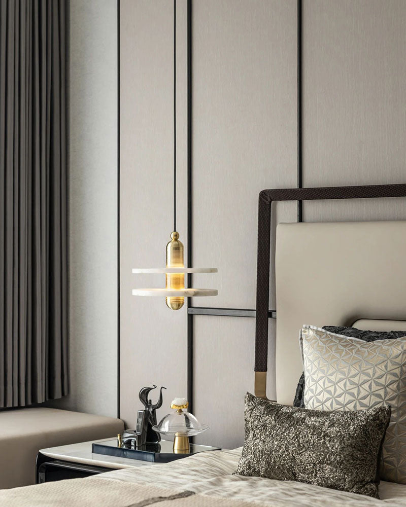 Luxurious pendant lamp hanging above a chic bed with textured pillows in contemporary bedroom