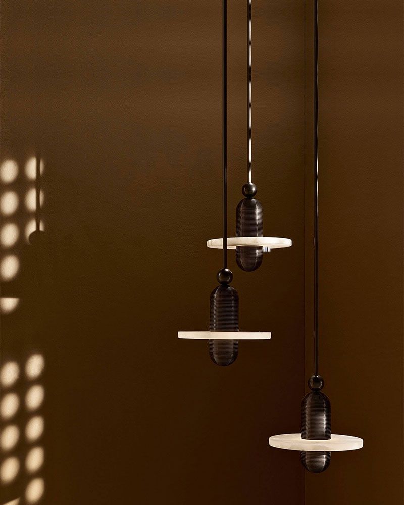 Three modern pendant lights with black and white design against dark background.