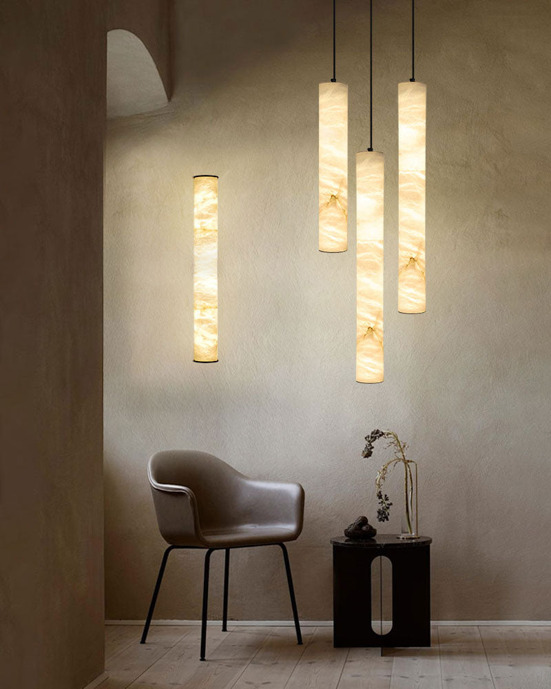 Alabaster cylindrical pendant lamps hanging in a minimalist room with modern furniture.