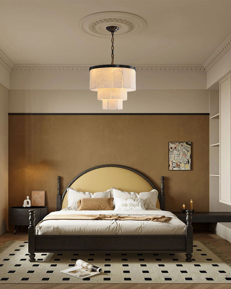 Stylish bedroom featuring a modern chandelier and gray bed with gold accents.