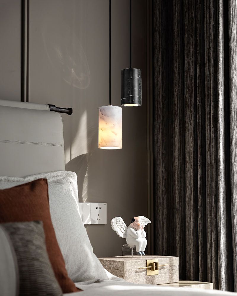 Elegant bedroom with cylinder pendant lamp above a bedside table and decorative statue.