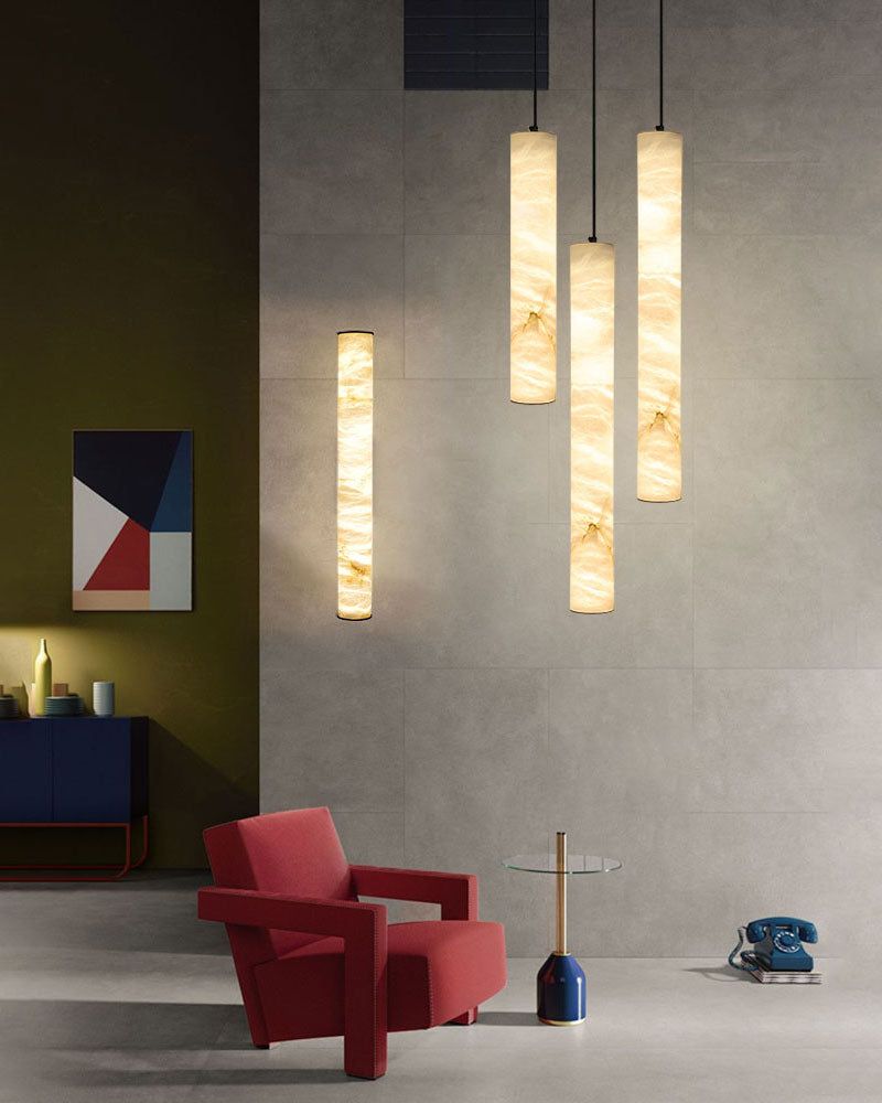 Alabaster pendant lamps hang above a red armchair in a modern interior design.