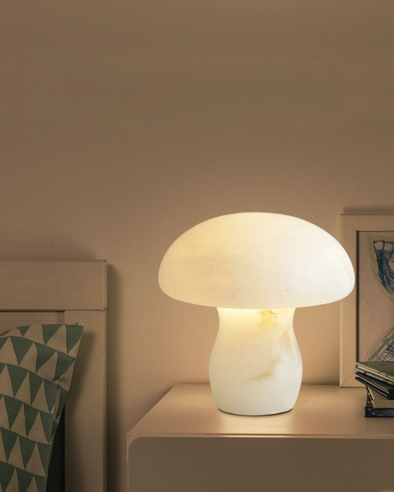 White mushroom lamp glowing warmly on nightstand beside decorative pillow and art.