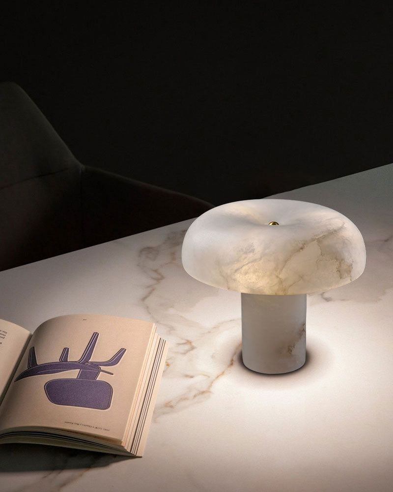 Elegant white marble table lamp with rounded shade illuminating marble table beside a book.