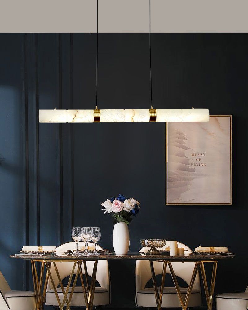 Horizontal alabaster LED pendant lamp above a stylish dining table with flowers.