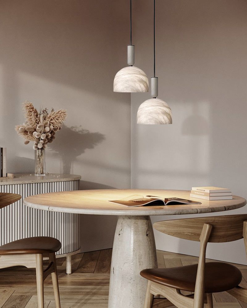 White marble pendant lights above a round dining table in a modern kitchen