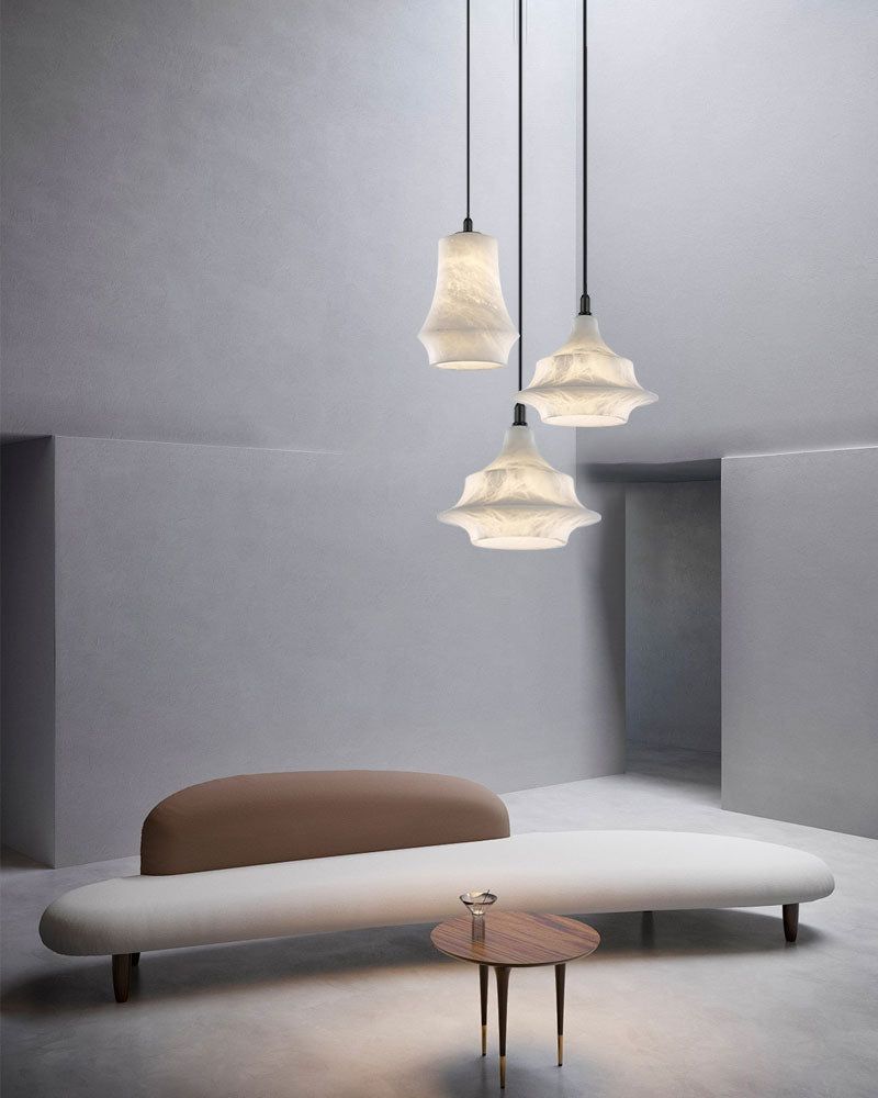 Modern sitting area with three alabaster pendant lamps above a beige curved sofa.