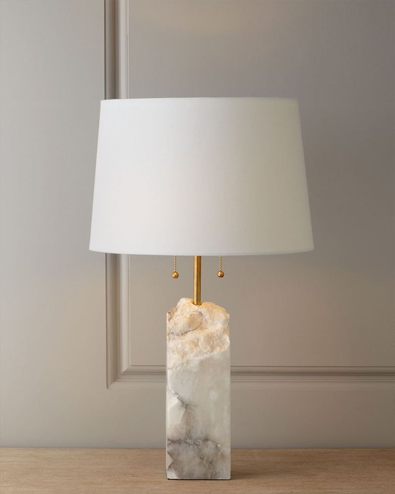 Stylish 15" alabaster table lamp with white linen shade on a wooden table.
