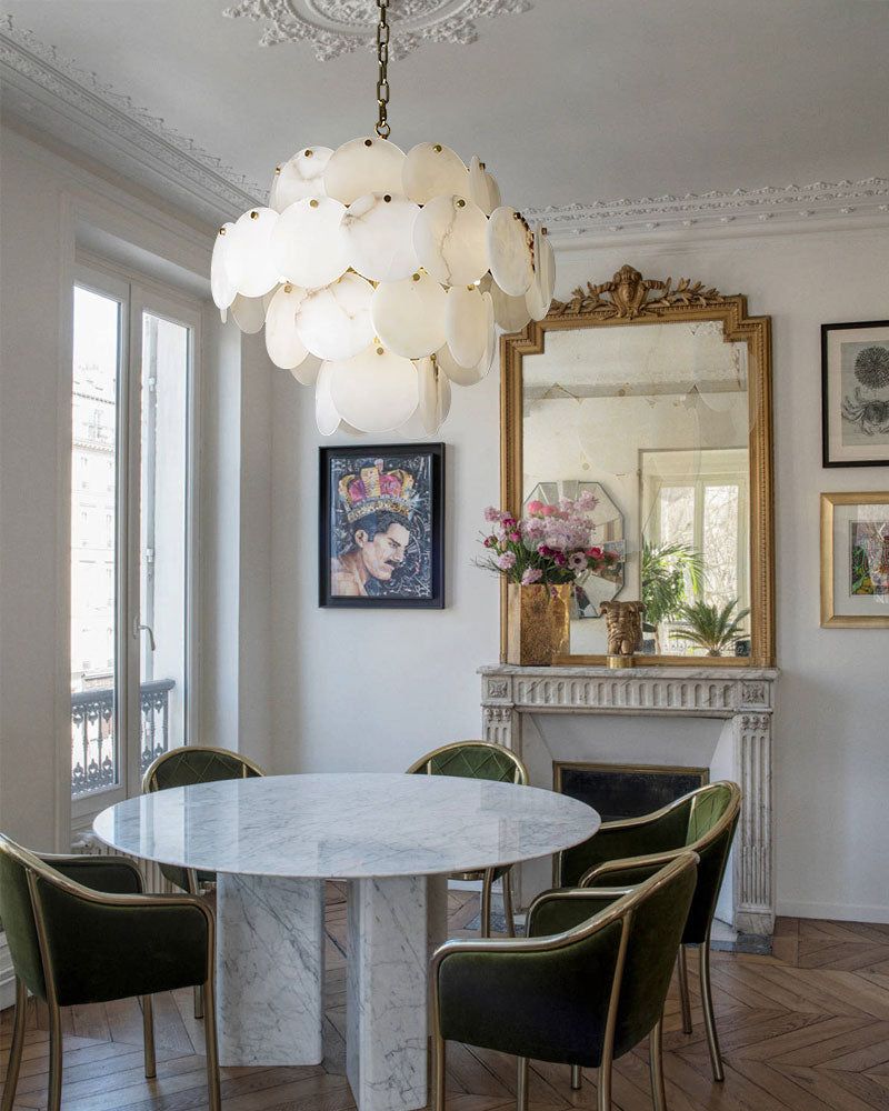 Elegant LED chandelier with Spanish marble shells above a round marble dining table.
