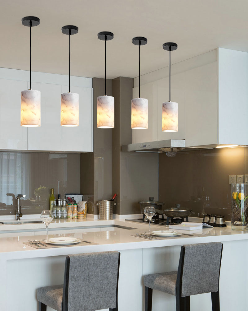Five marble design pendant lamps over a sleek kitchen island with dining setup.