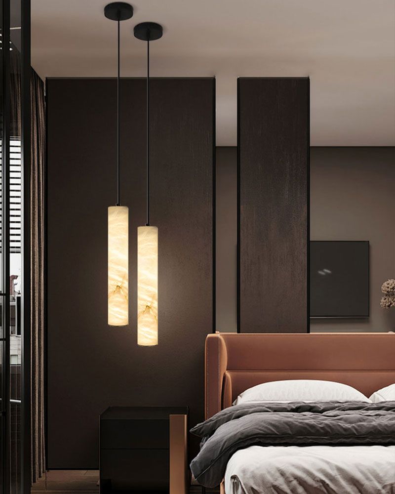 Alabaster cylindrical pendant lamps above a modern bed in a stylish bedroom.