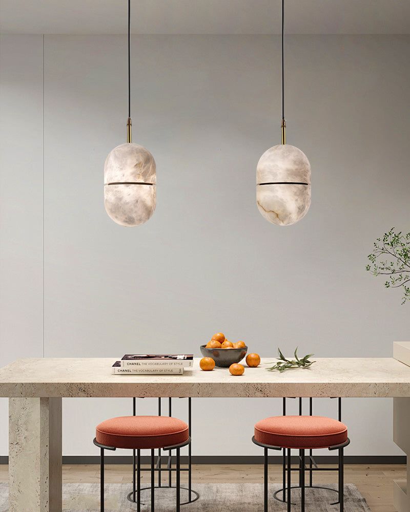 Modern alabaster pendant lights above a chic dining table with decorative bowl of oranges.