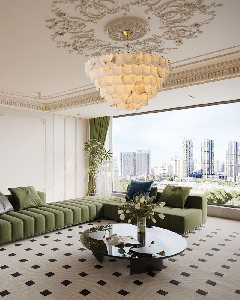 Long linear LED chandelier with marble shells above modern green couch and city view.