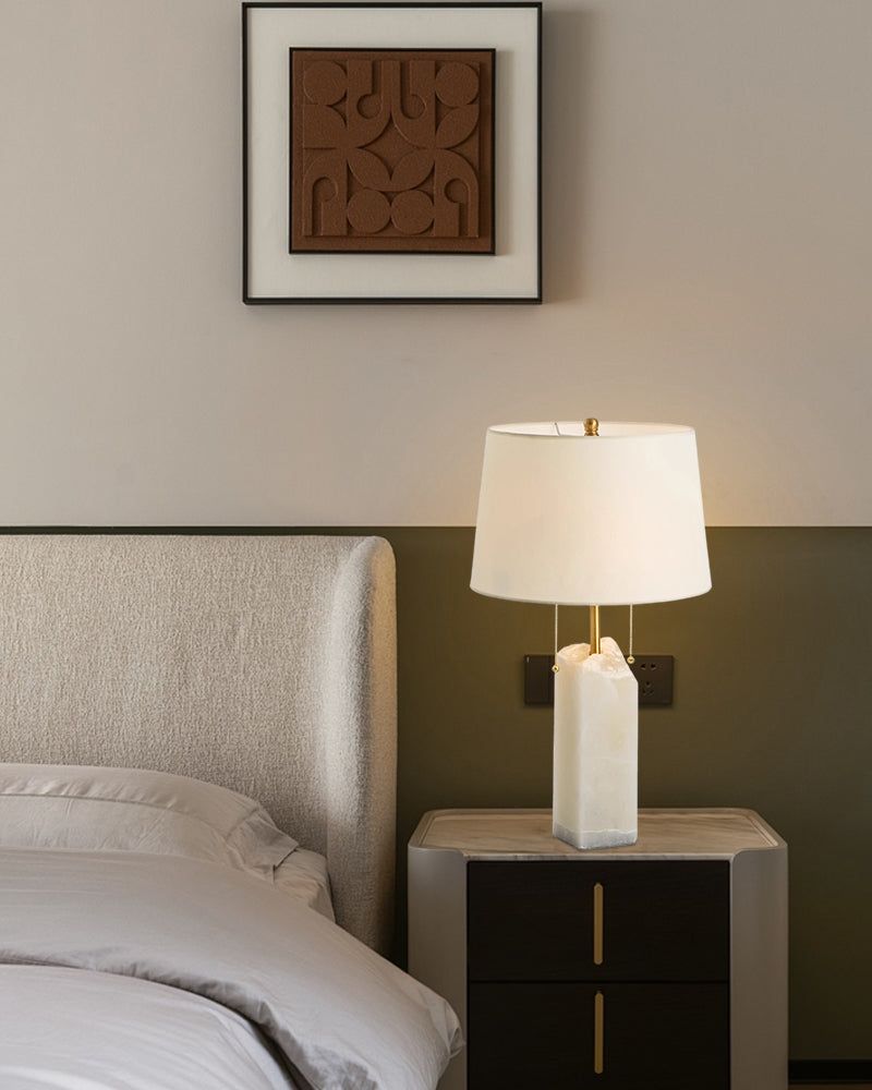 Chic alabaster table lamp with linen shade on nightstand in modern bedroom decor.