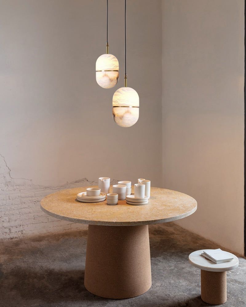 Stylish alabaster pendant lights over a modern dining table with dishware
