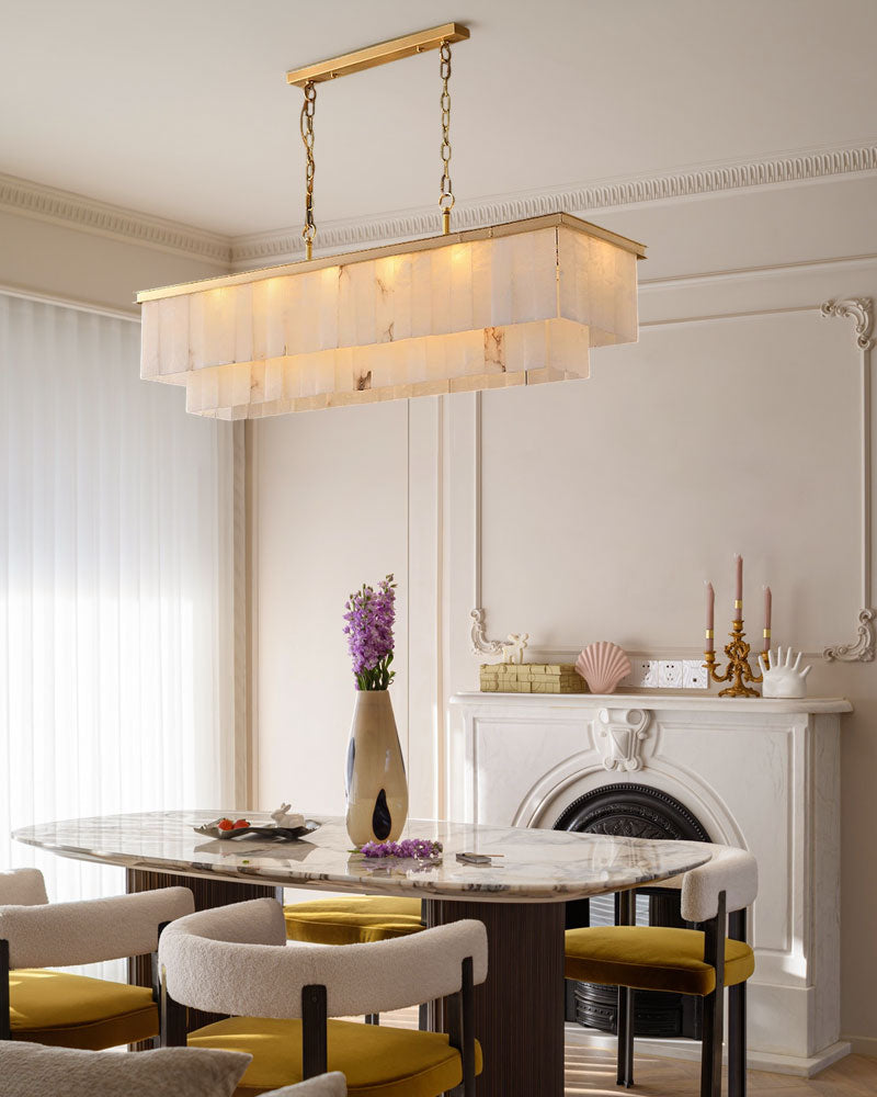 Dining area with a brass pendant light above a marble table and stylish chairs.