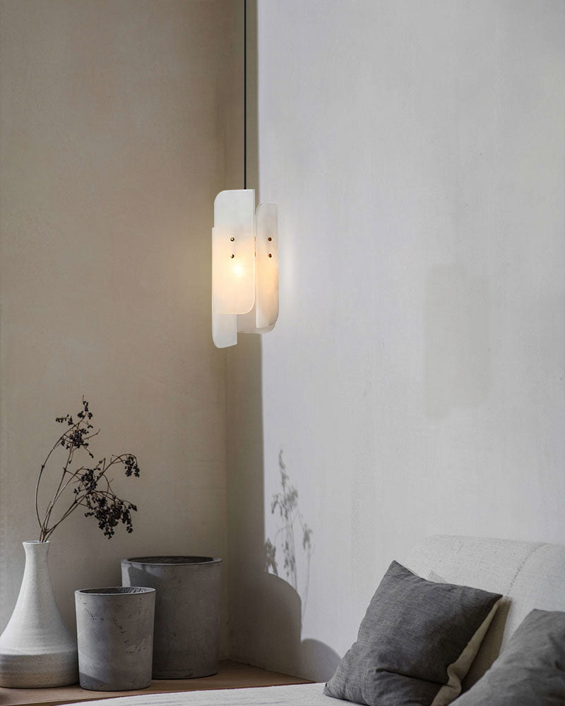 Alabaster pendant lamp illuminating minimalist space with gray and white vases.