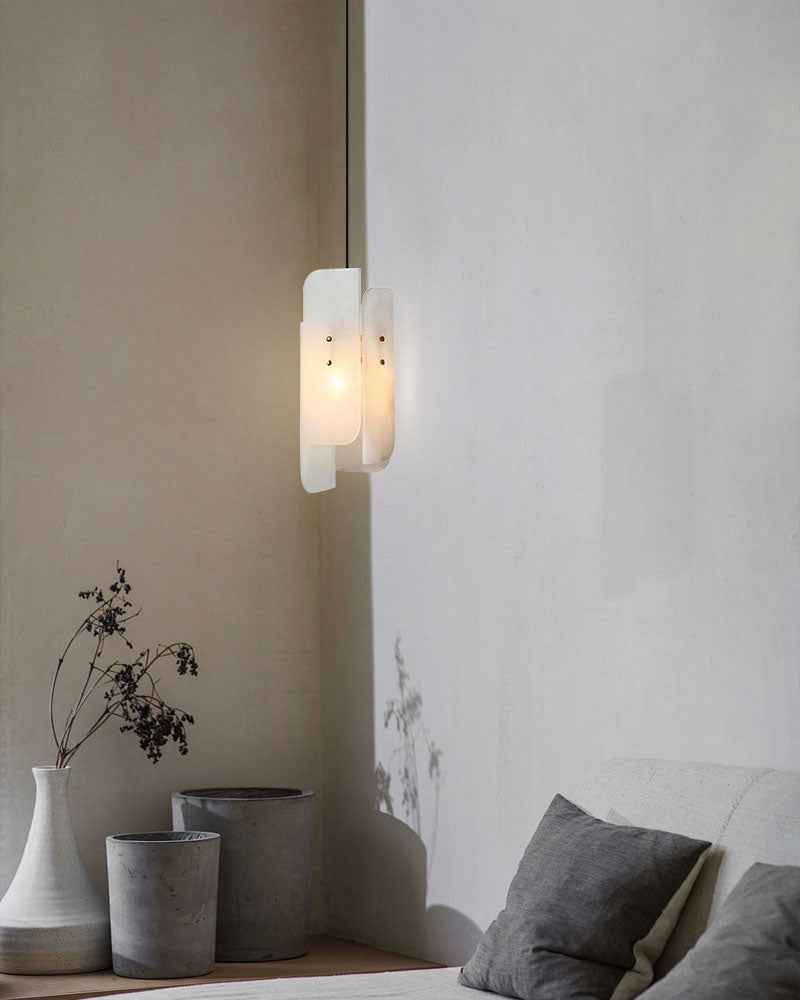 Alabaster pendant lamp illuminating minimalist space with gray and white vases.