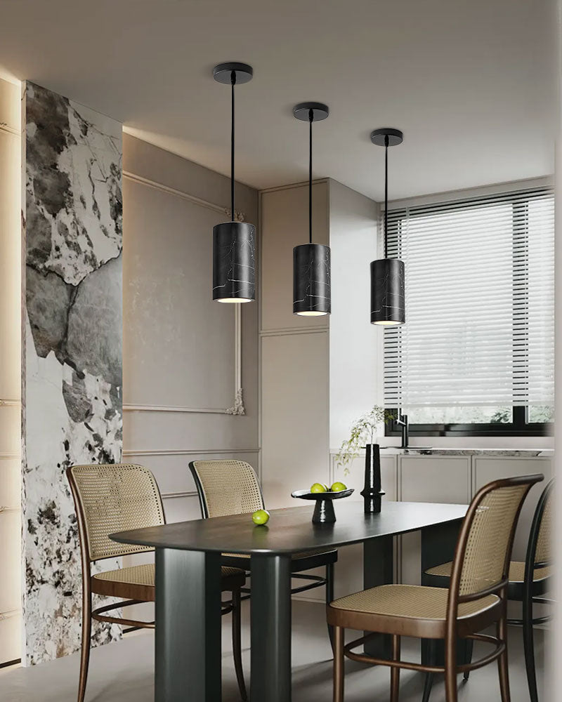 Three black cylinder pendant lamps over a modern dining table in sleek interior design