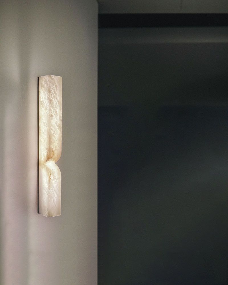 Alabaster wall sconce with modern curved design illuminating a contemporary space.