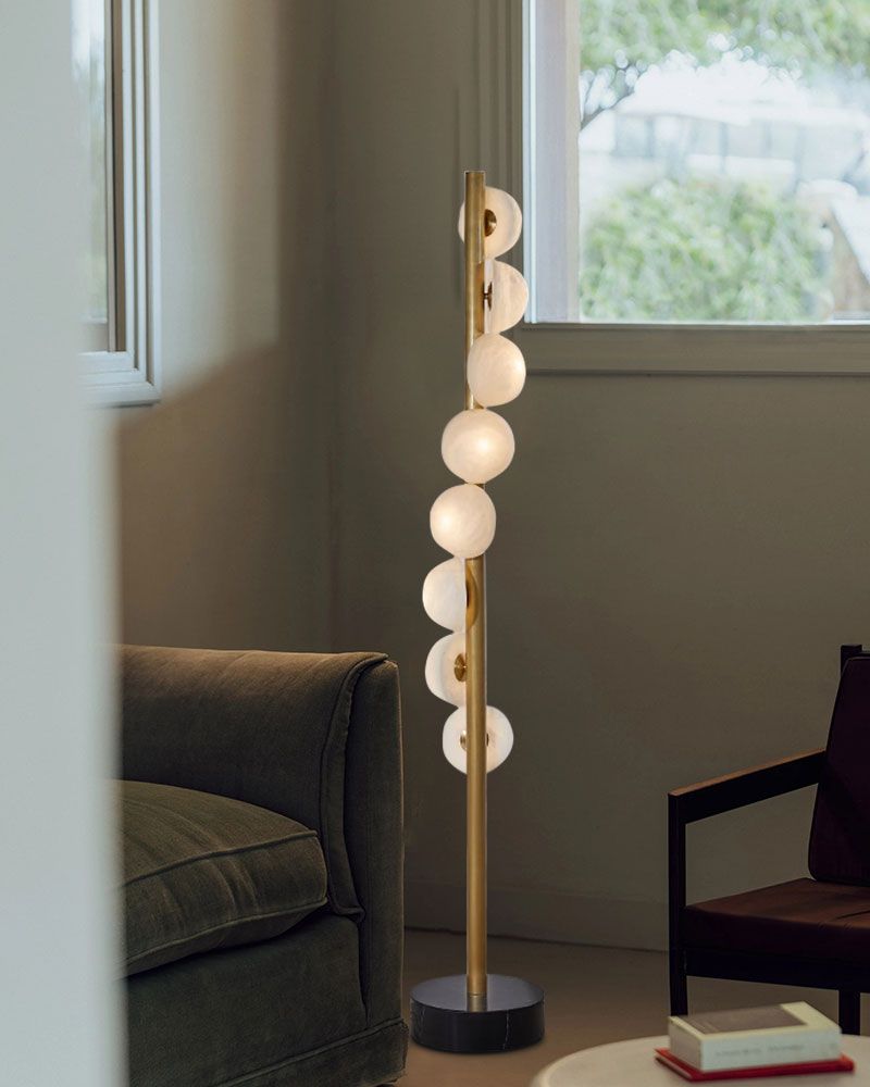 Brass skinny floor lamp with alabaster globes in stylish living room corner