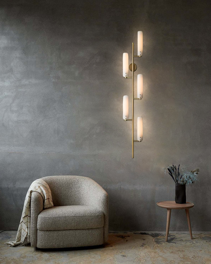 Curved brass wall sconce with milk glass shades illuminating modern sitting area