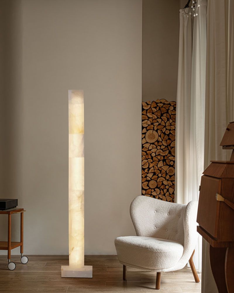 Elegant alabaster column lamp beside plush armchair in contemporary living room