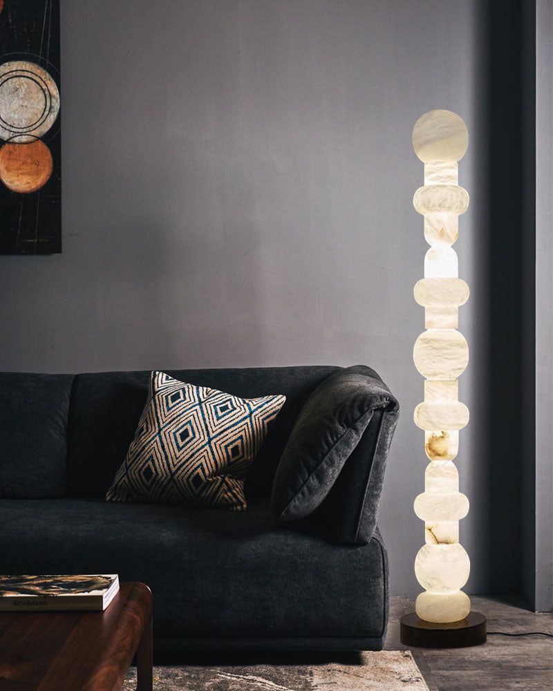 Geometric alabaster floor lamp casting warm light in contemporary room with black sofa
