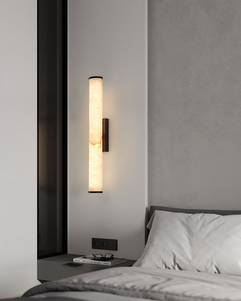 Cylindrical alabaster wall sconce lamp illuminating contemporary bedroom design