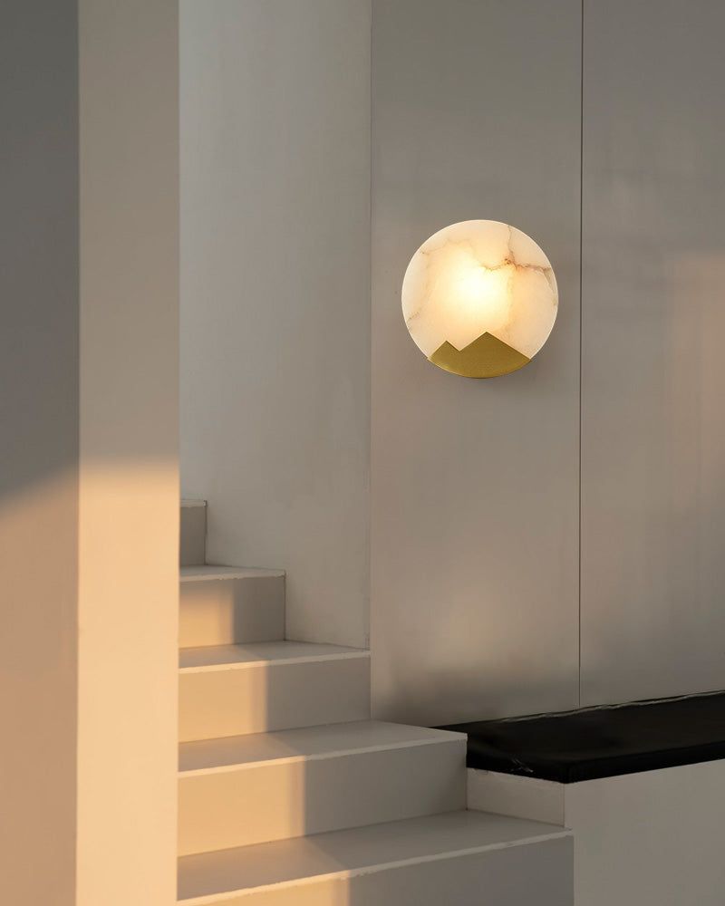 Modern alabaster LED wall sconce with mountain design above staircase