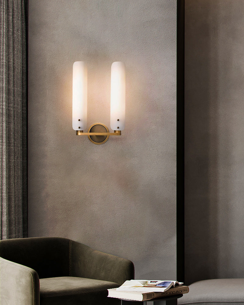 Modern brass wall sconce with frosted glass shades in chic living room setting