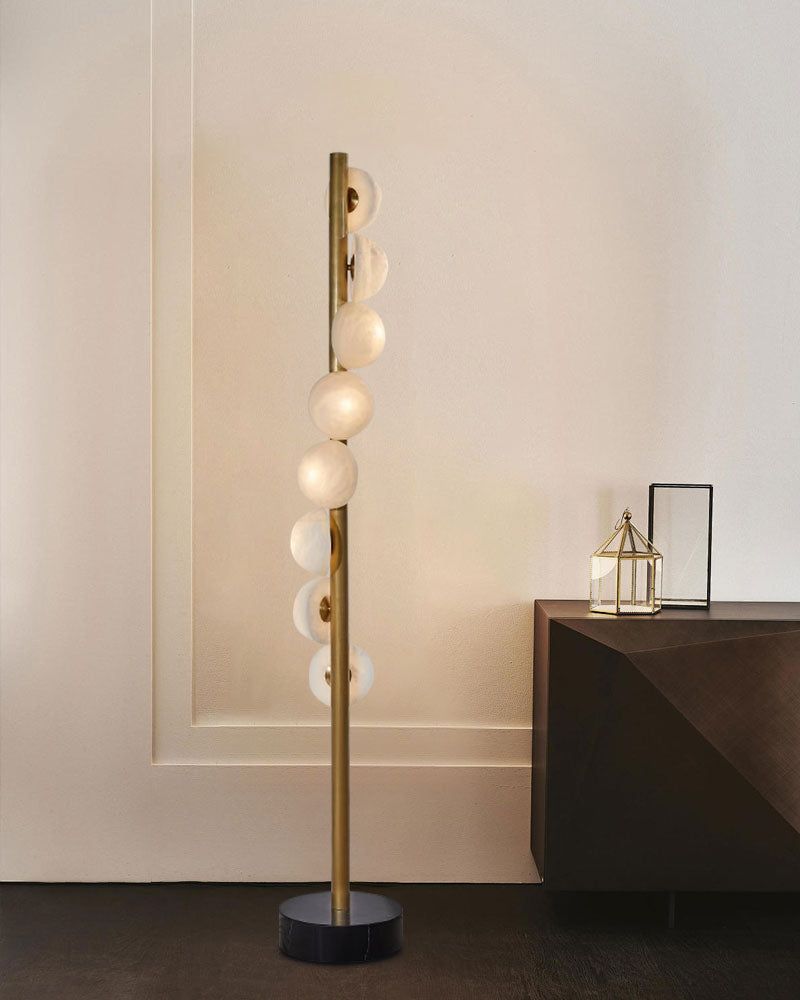 Sleek vertical brass floor lamp with alabaster globes beside dark wood side table