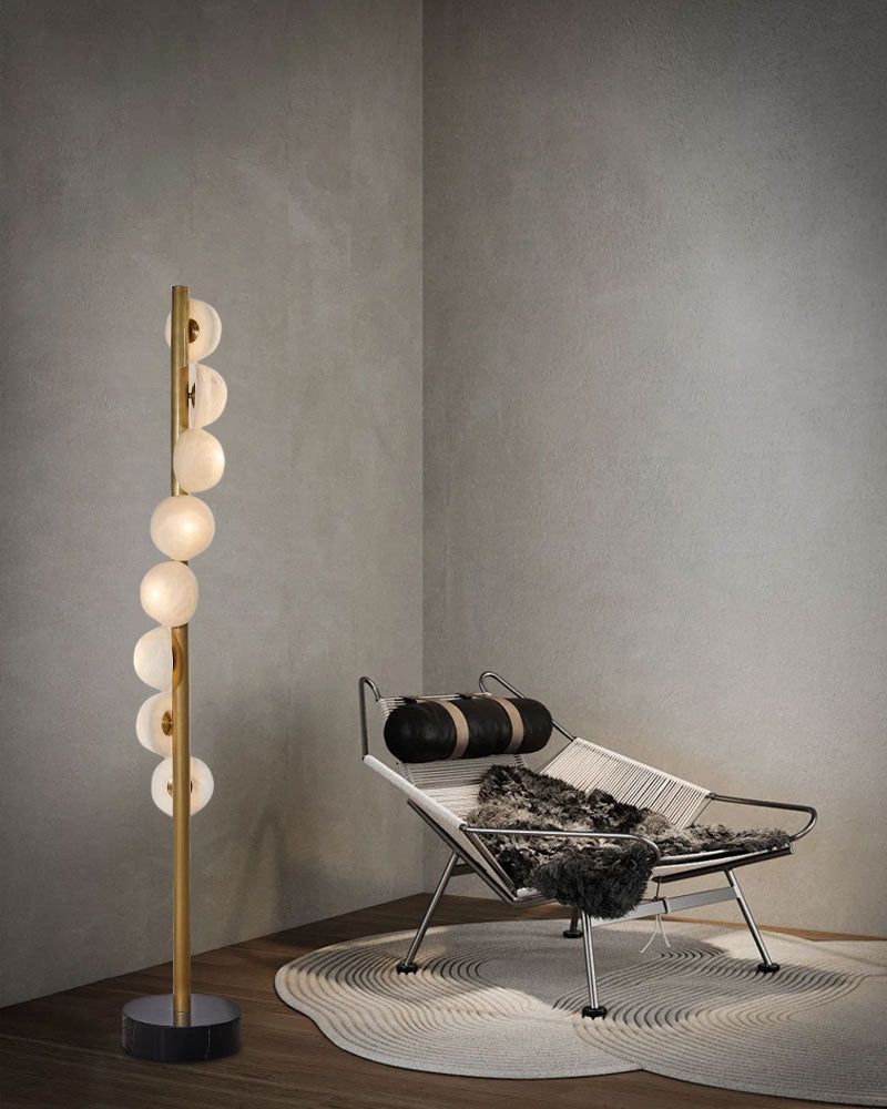 Sleek vertical brass floor lamp with alabaster globes in a cozy modern corner