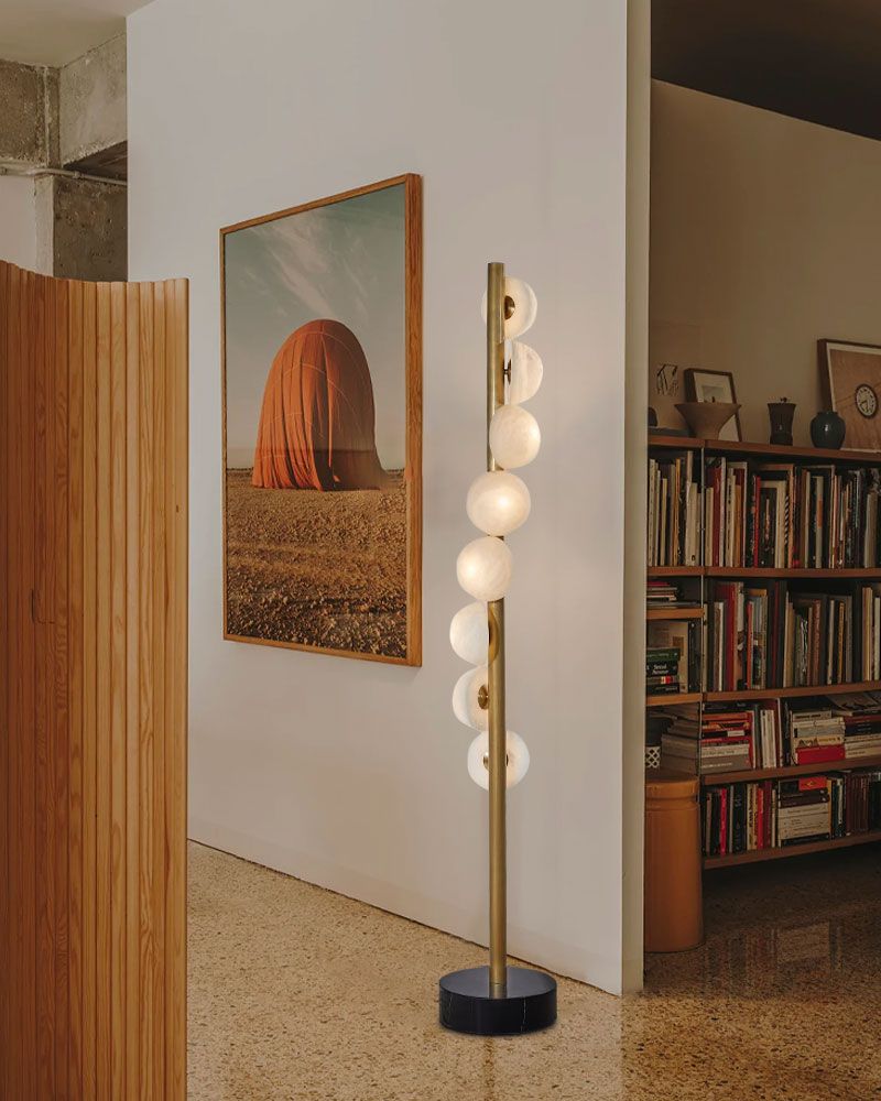 Stylish brass skinny floor lamp with alabaster globes in cozy modern nook