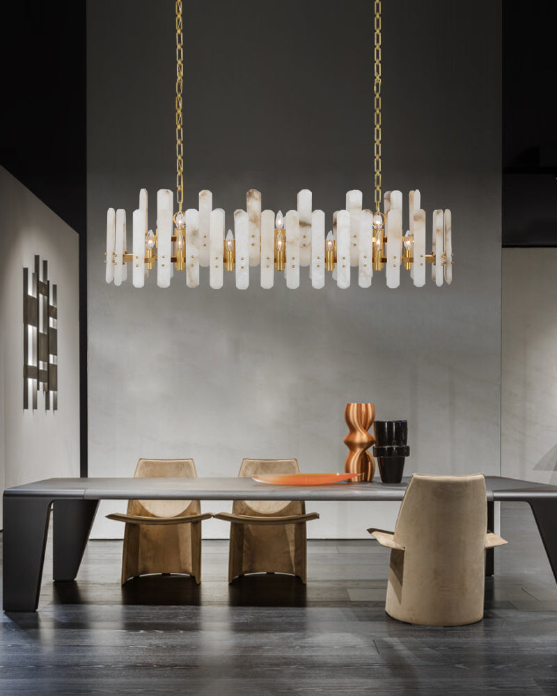 A modern dining room illuminated by an artistic marble chandelier composed of many cylindrical glass shades, hanging over a dark wood table surrounded by gold chairs