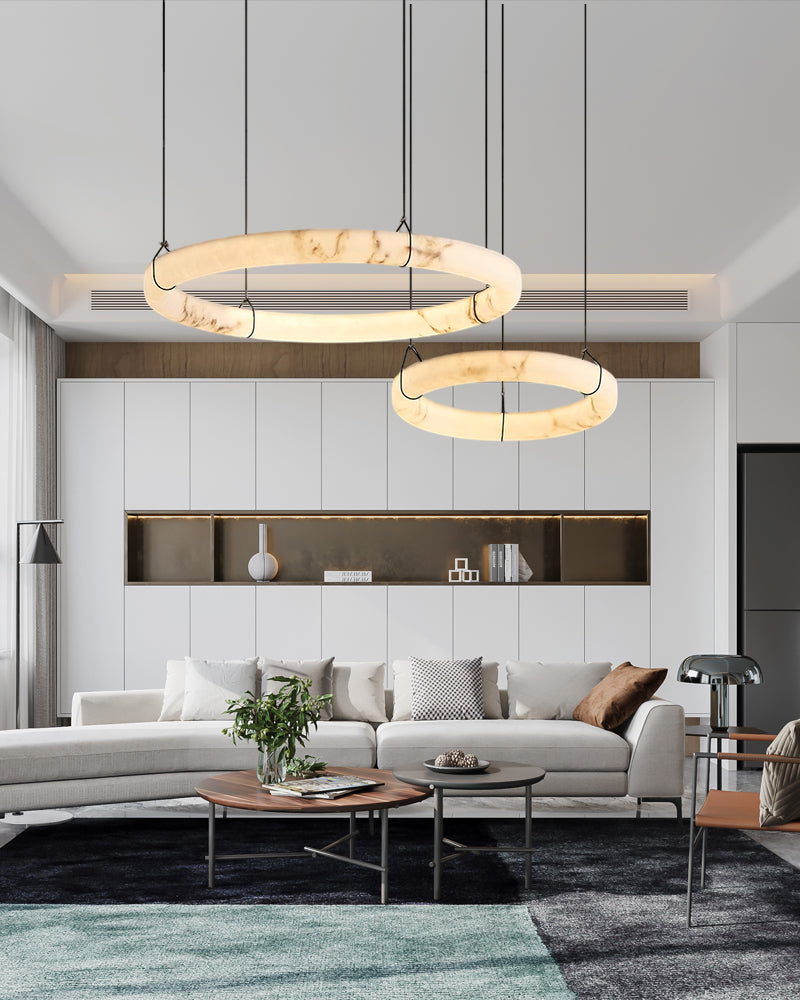 A modern living room featuring a stylish Circle Chandelier made of marble, suspended above a cozy seating area with a neutral color palette.