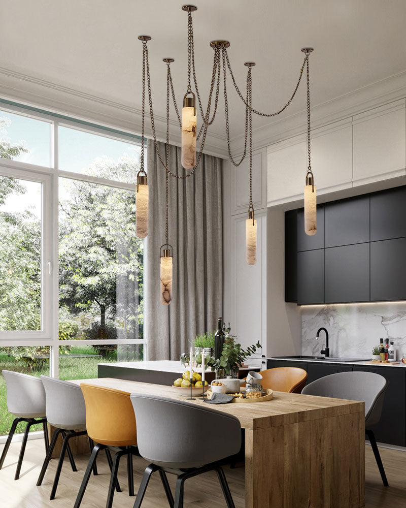 9-light brass LED pendant lamp above a modern dining table with garden view.