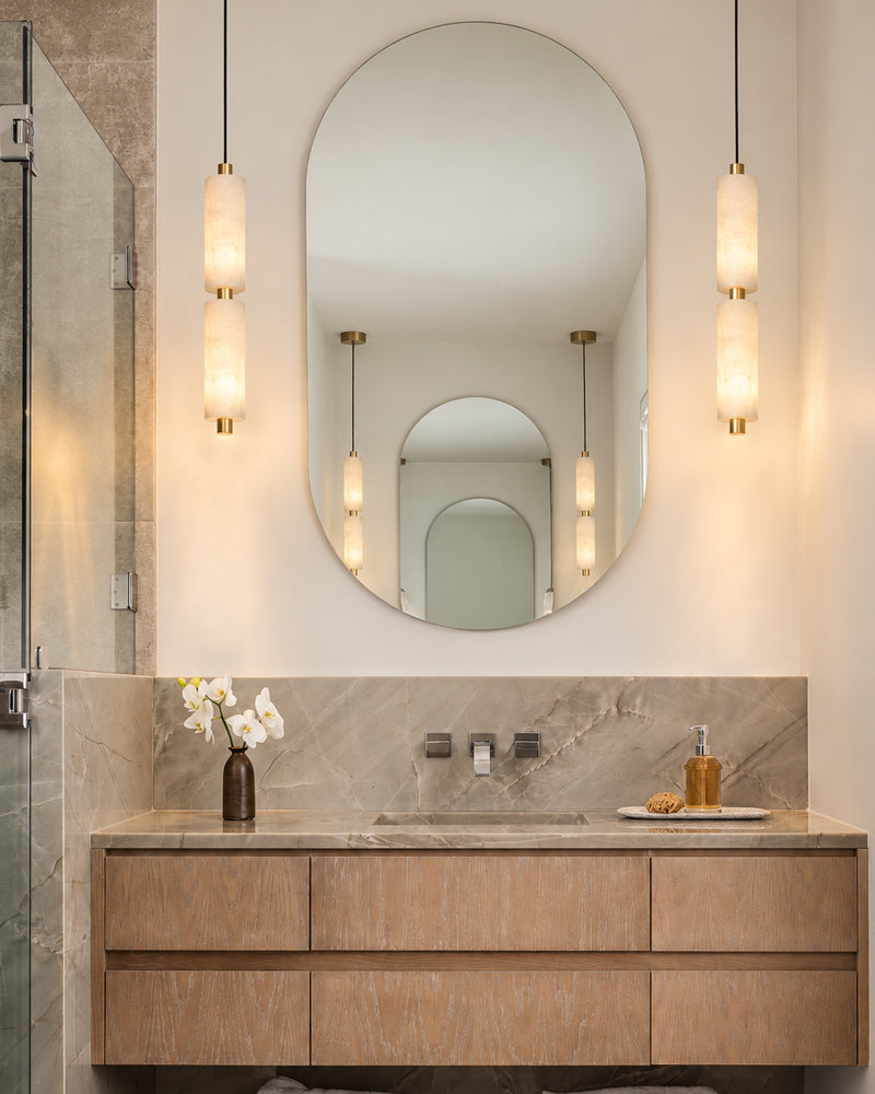 Brass pendant light cluster with vertical alabaster cylinder glass shades over vanity