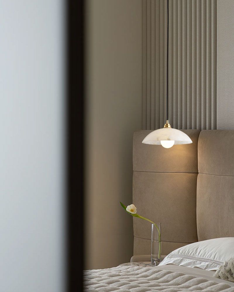 Natural stone pendant lamp illuminating modern bedroom with soft gray bedding.