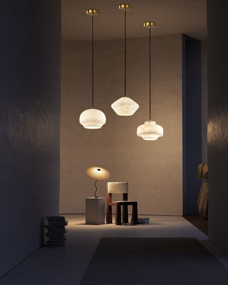 Three alabaster pendant lamps illuminating a stylish hallway with minimalist decor.