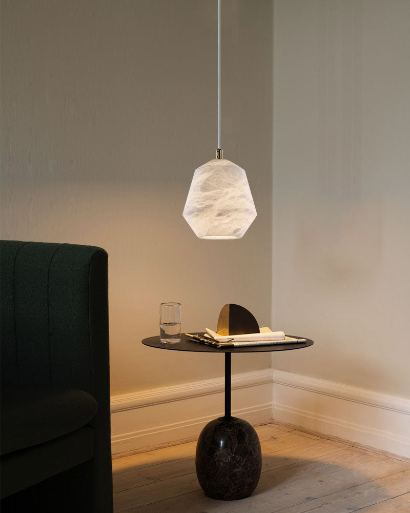 Alabaster pendant lamp above modern black side table with glass and decor.