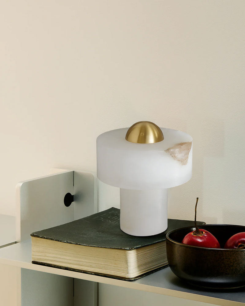 Stylish white and brass alabaster table lamp on a shelf next to a bowl of apples.