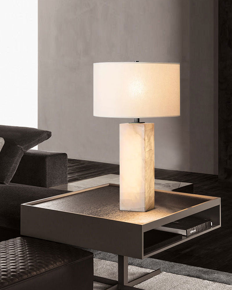 Alabaster table lamp with cream shade illuminating a modern nightstand in chic interior.