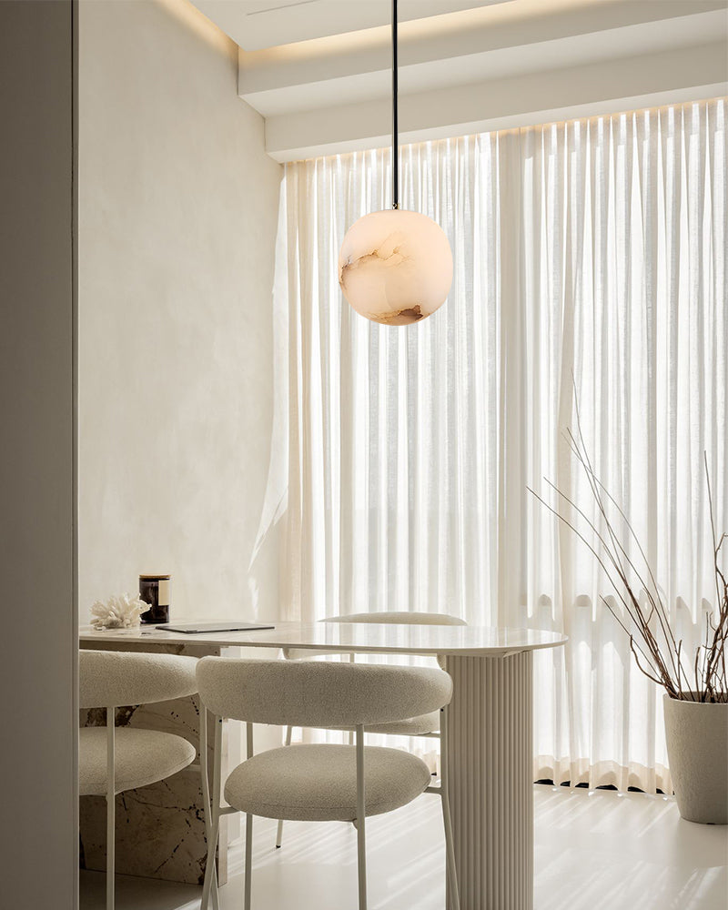 Elegant marble pendant lamp illuminating a modern dining area with soft textures