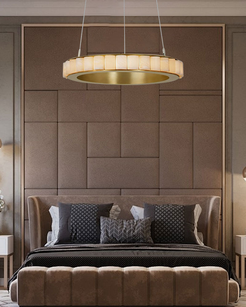 Round chandelier lamp with alabaster shade above a plush upholstered bed in neutral decor.