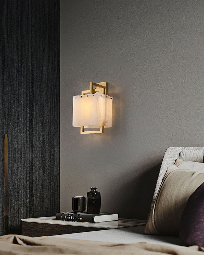 Stylish wall lamp with brass frame and marble shade in modern bedroom setting.