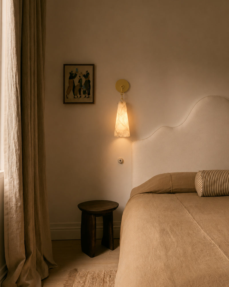 Conical alabaster wall sconce with round metal backplate, warm light